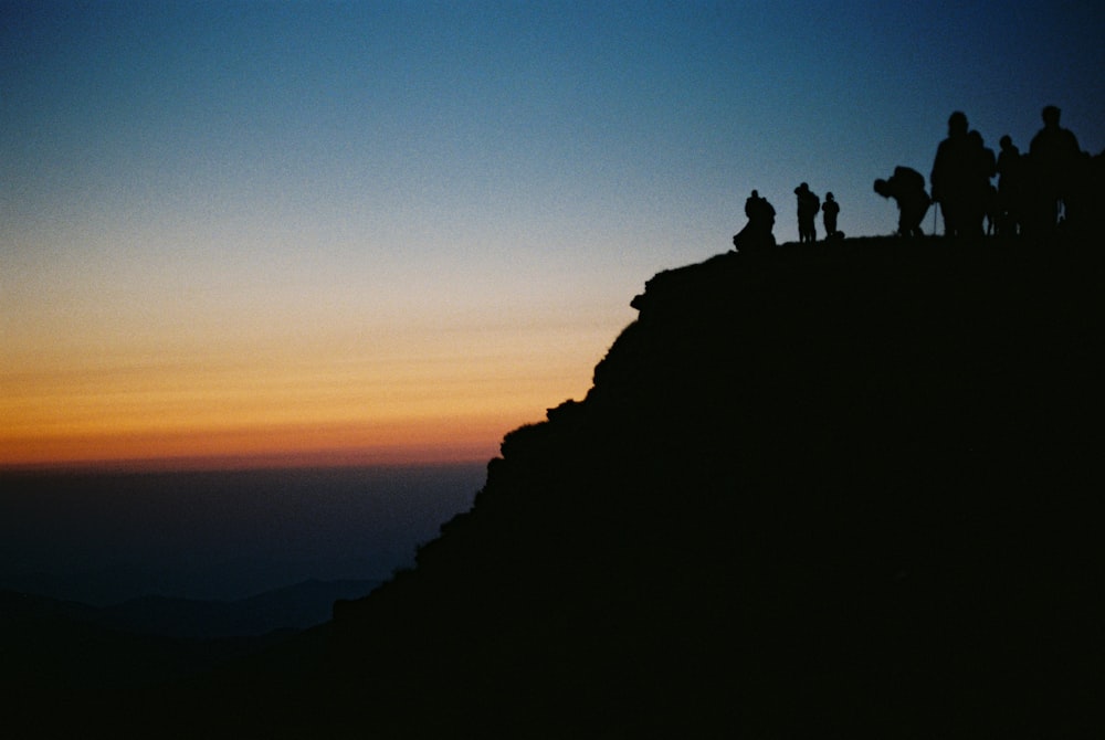 silhouette of people on top of mountain during sunset