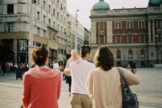 A professional group in business attire walking through a sunlit Lisbon plaza with classic architecture.