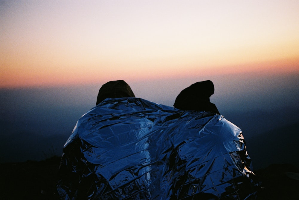 person in blue jacket and black knit cap sitting on rock formation during daytime