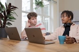man and woman sitting at table using macbook