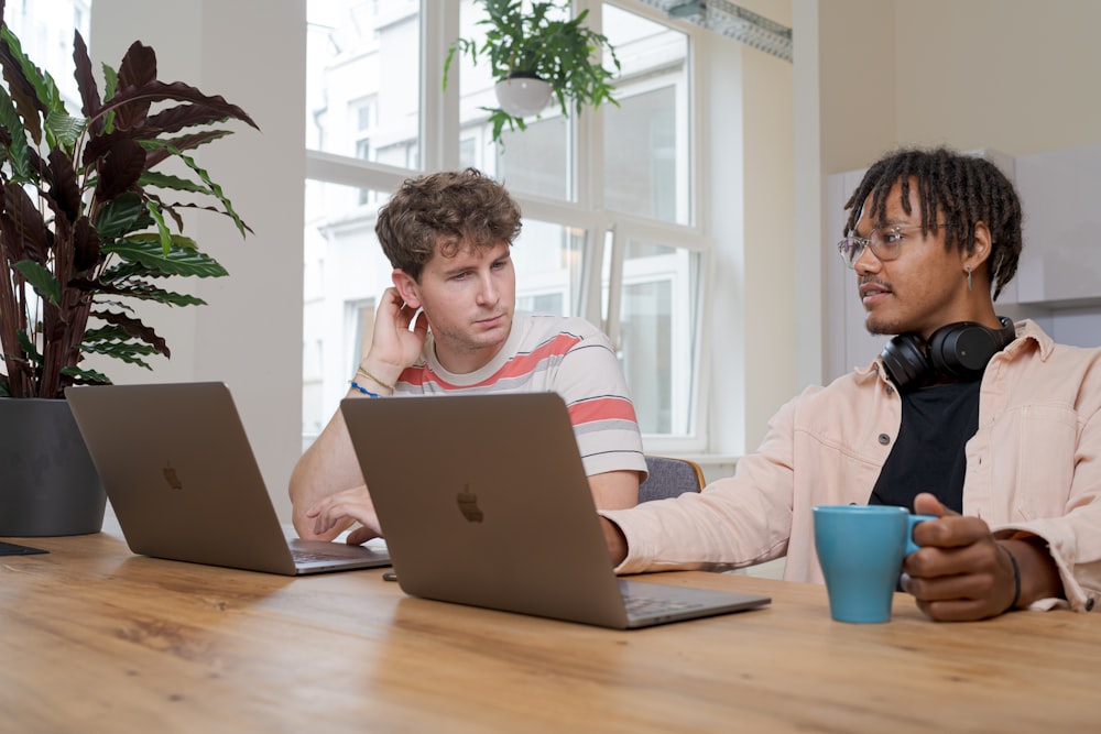 man and woman sitting at table using macbook