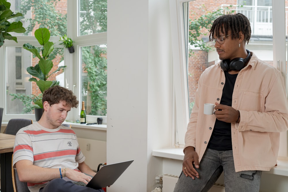 man in gray dress shirt sitting on chair using macbook