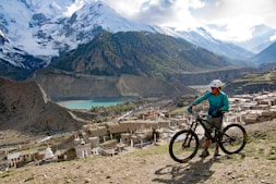 man in green shirt riding bicycle on mountain during daytime