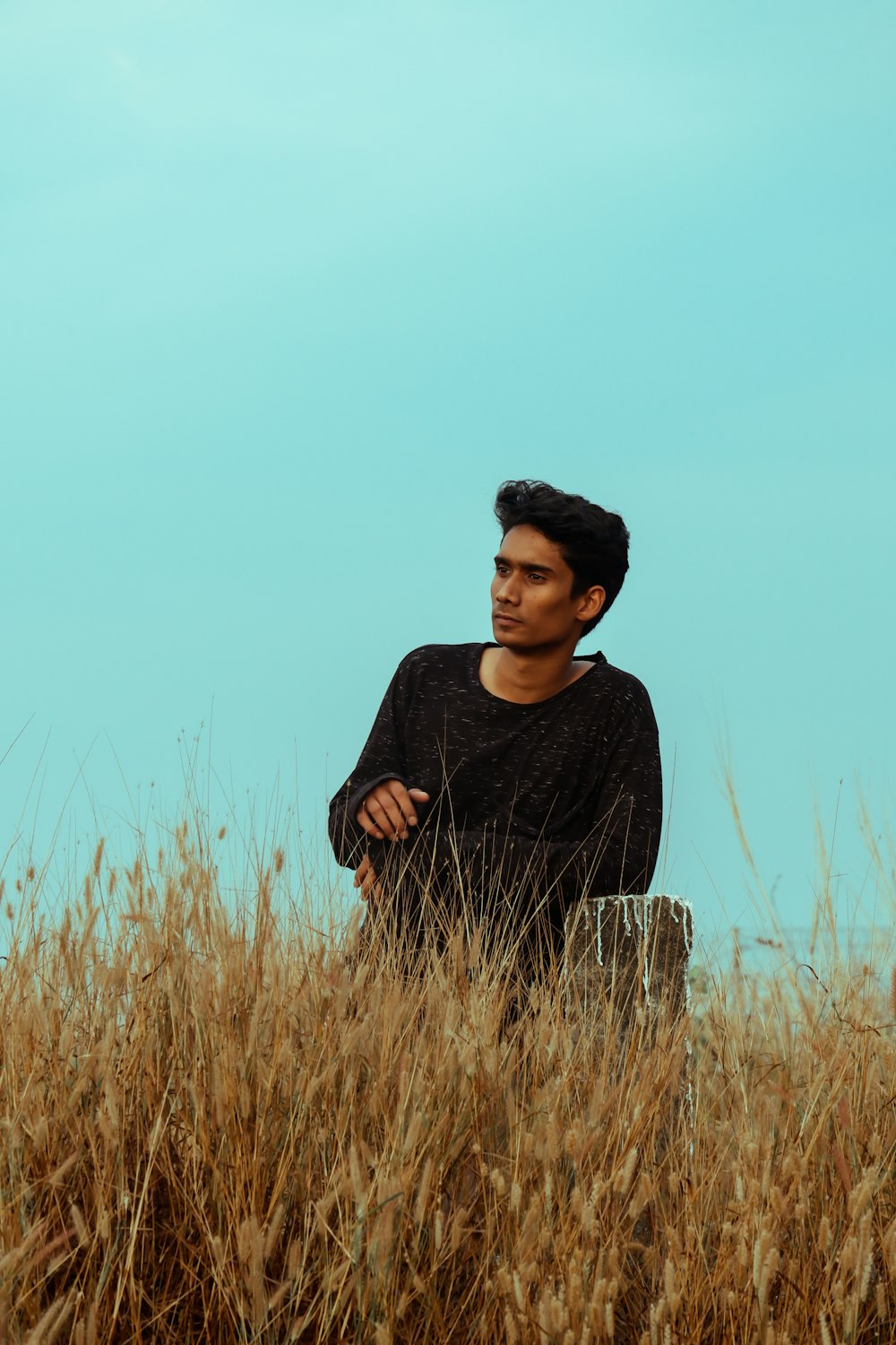 man in black sweater standing on brown grass field during daytime