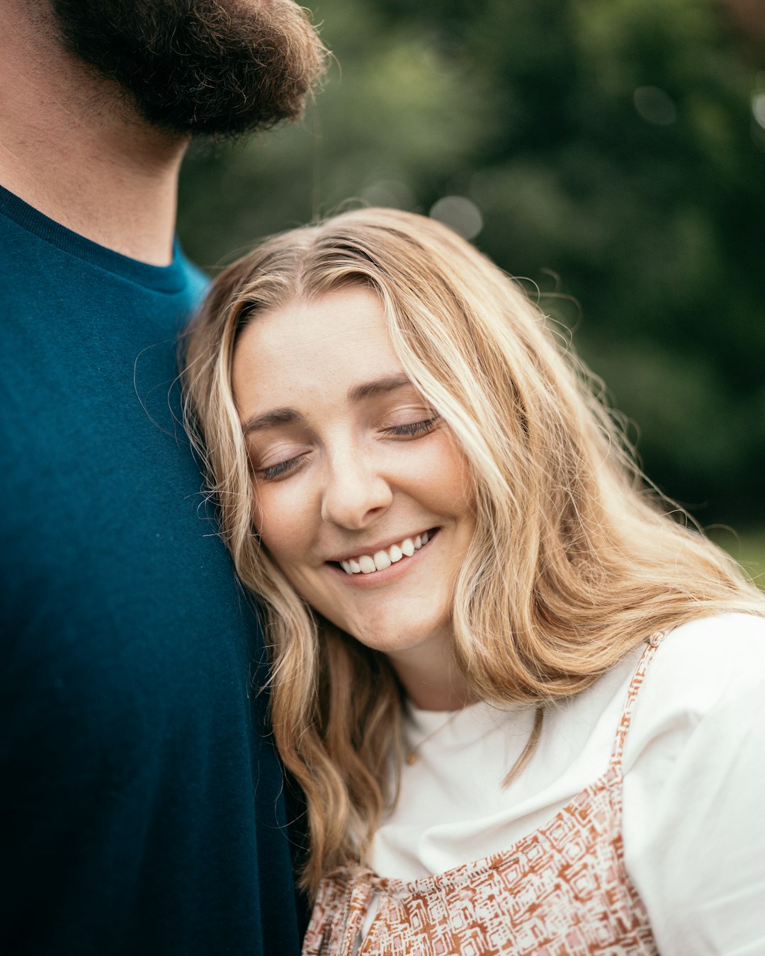 man in blue crew neck shirt smiling beside woman in white shirt