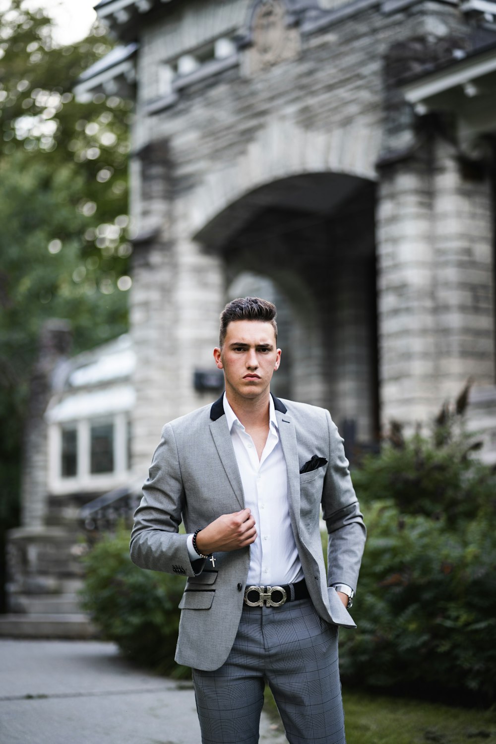 man in gray suit jacket standing near white concrete building during daytime