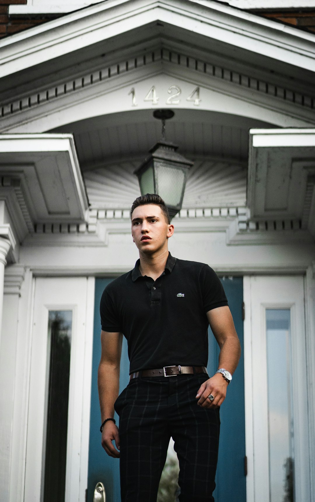 man in black polo shirt standing near white wooden door