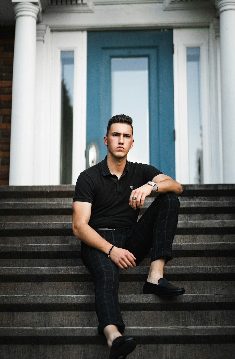 man in black crew neck t-shirt and blue denim jeans sitting on gray concrete stairs