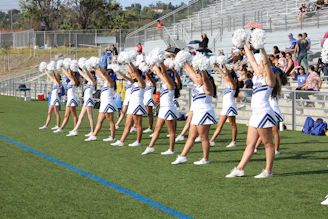 Cheerleaders in matching uniforms mid-routine with bright smiles.