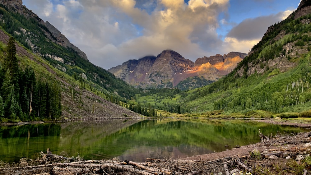 green mountains beside lake under blue sky and white clouds during daytime