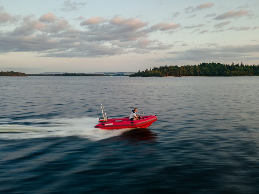 red and white boat on sea under white clouds during daytime