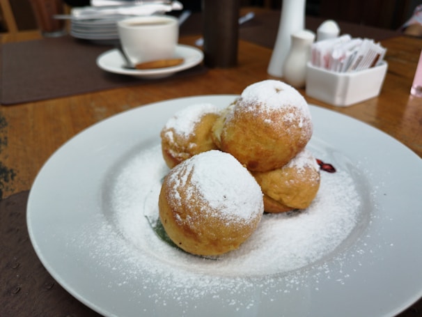 Close-up of golden, hand-rolled Ukrainian blintzes dusted with powdered sugar on a fine porcelain plate.