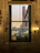 Elegant hotel room with a large window overlooking a vibrant city plaza at sunset.