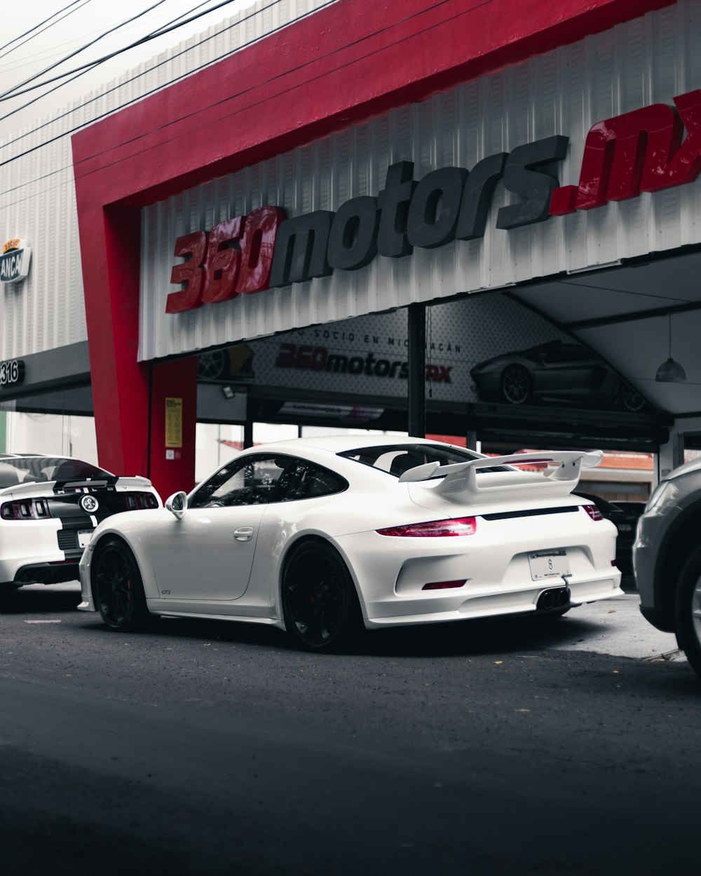 white porsche 911 parked in front of white and red building