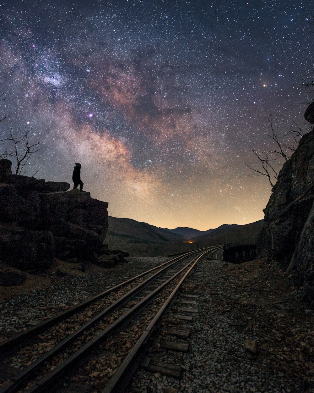 man standing on train rail during night time