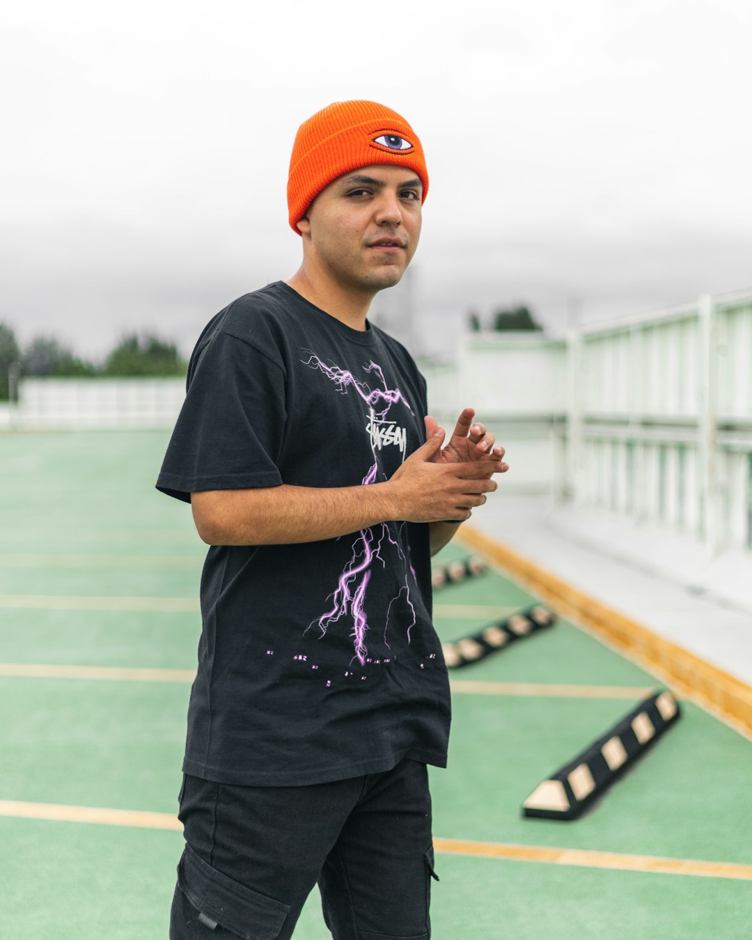 man in black crew neck t-shirt and orange cap standing on track field during daytime