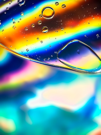 Colorful abstract display with rainbow-like swirls. Several bubbles appear on the surface, with vivid colors including blues, oranges, and yellows blending into each other.