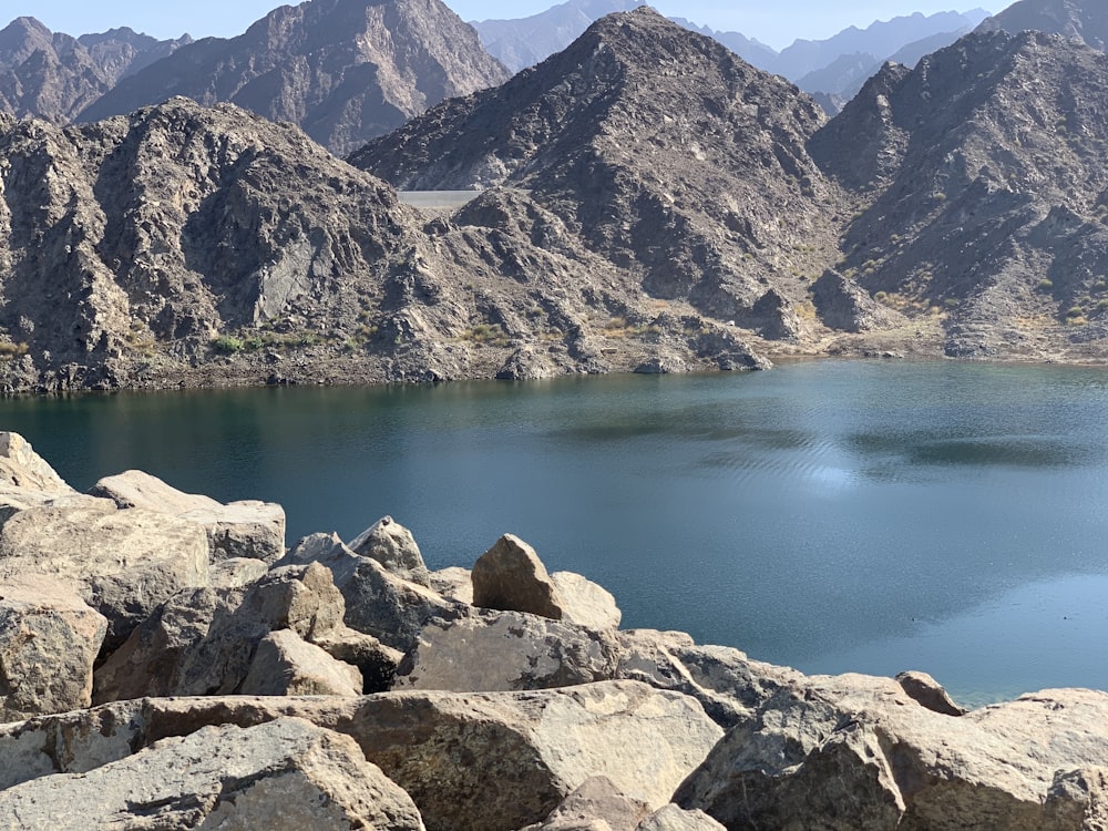 brown rocky mountain beside lake during daytime