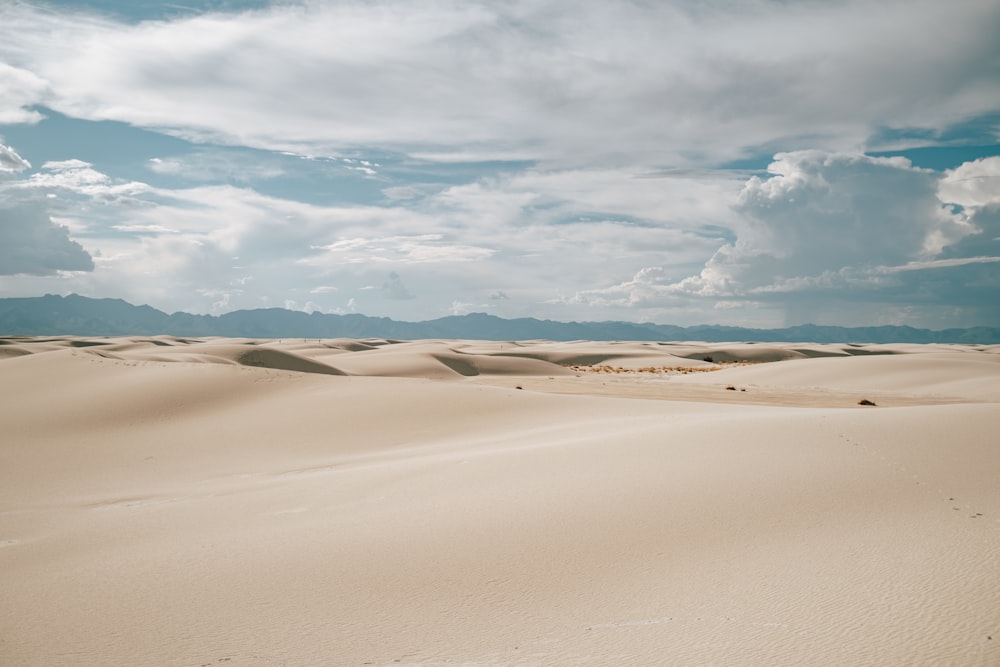 brown sand under white clouds and blue sky during daytime