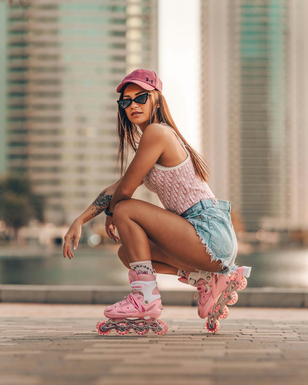 woman in blue tank top and blue denim shorts sitting on brown concrete floor during daytime