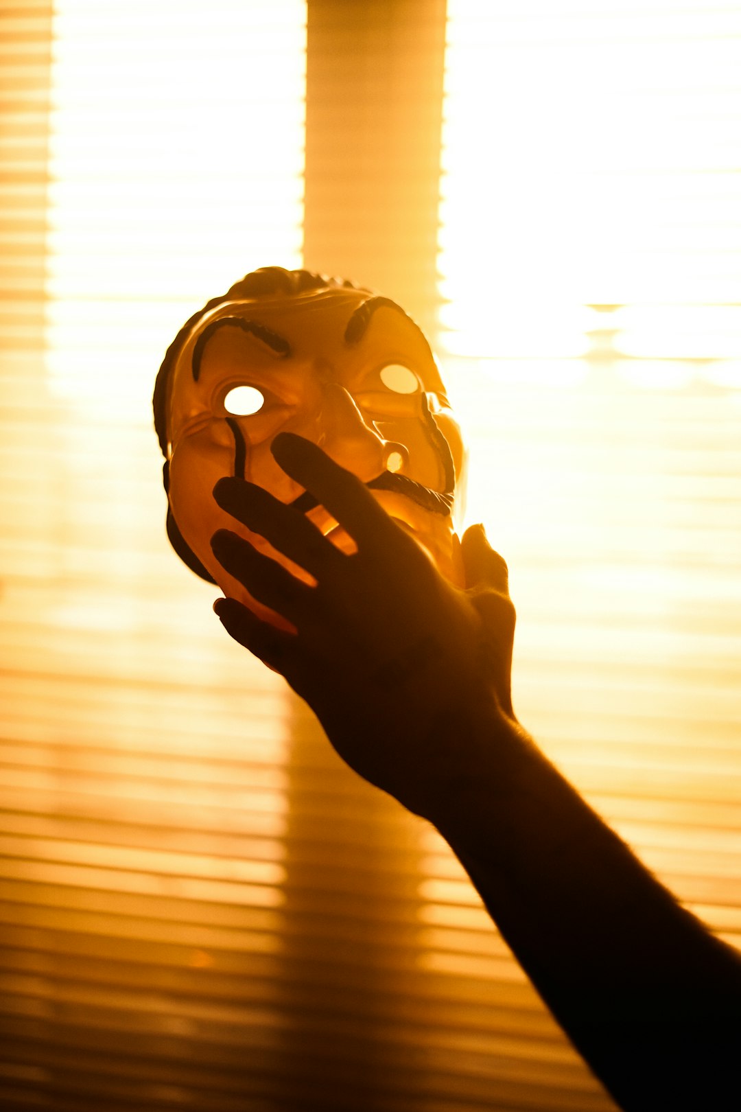 person holding brown wooden mask