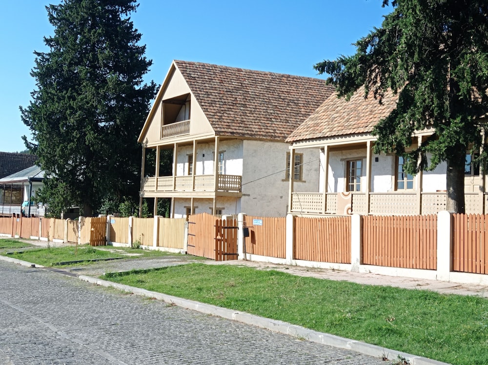 brown and white wooden house near green trees under blue sky during daytime