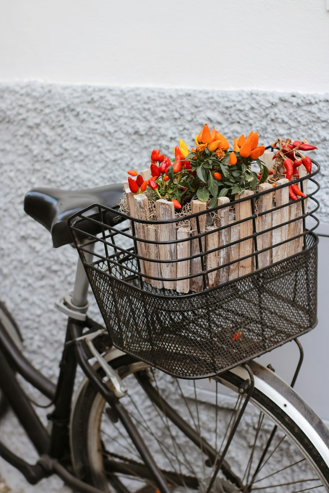 black metal basket with orange and red flowers on bicycle