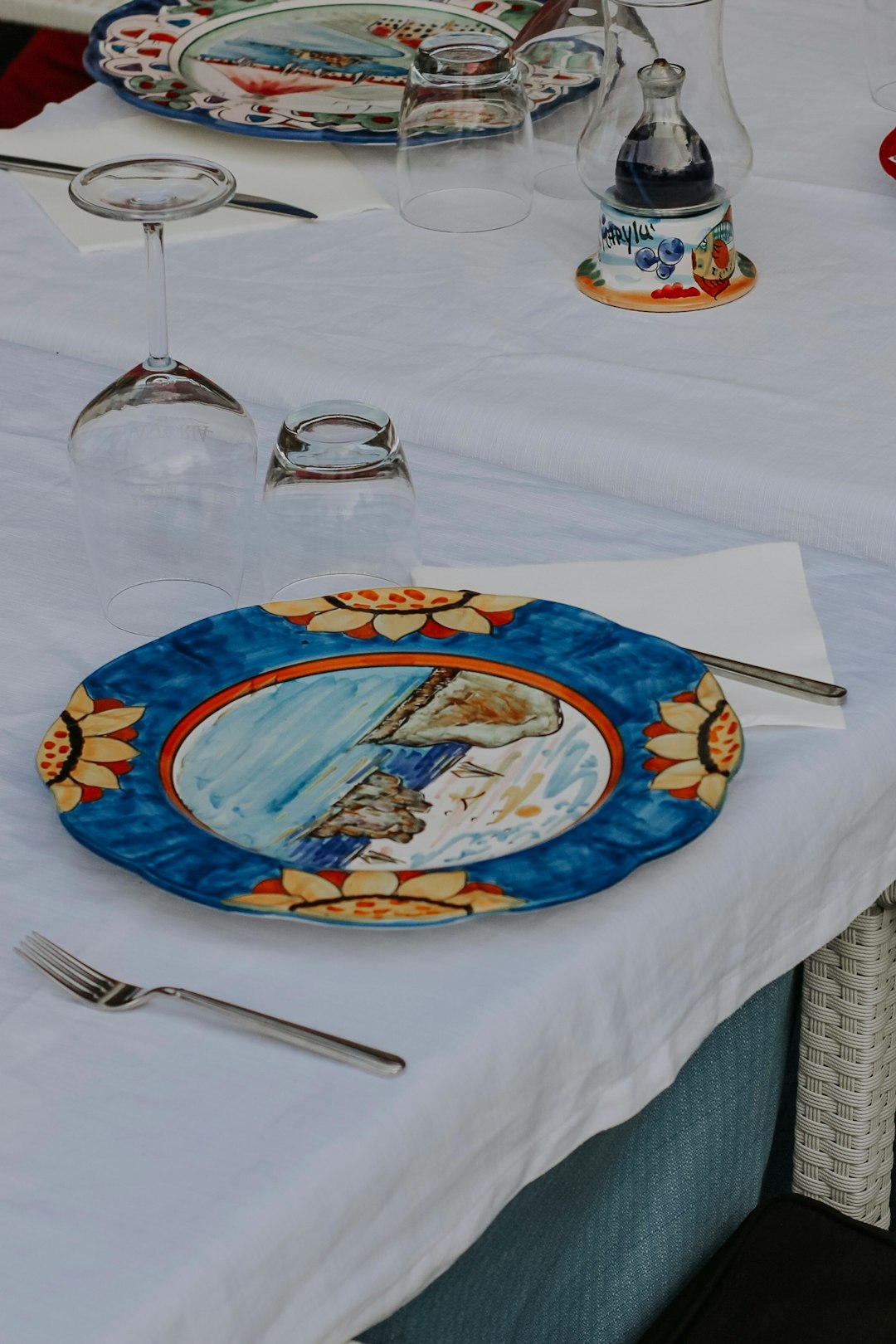 blue and white ceramic plate with stainless steel fork and bread knife on white table cloth