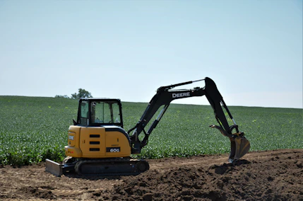 yellow and black excavator on brown soil
