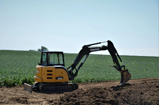 yellow and black excavator on brown soil