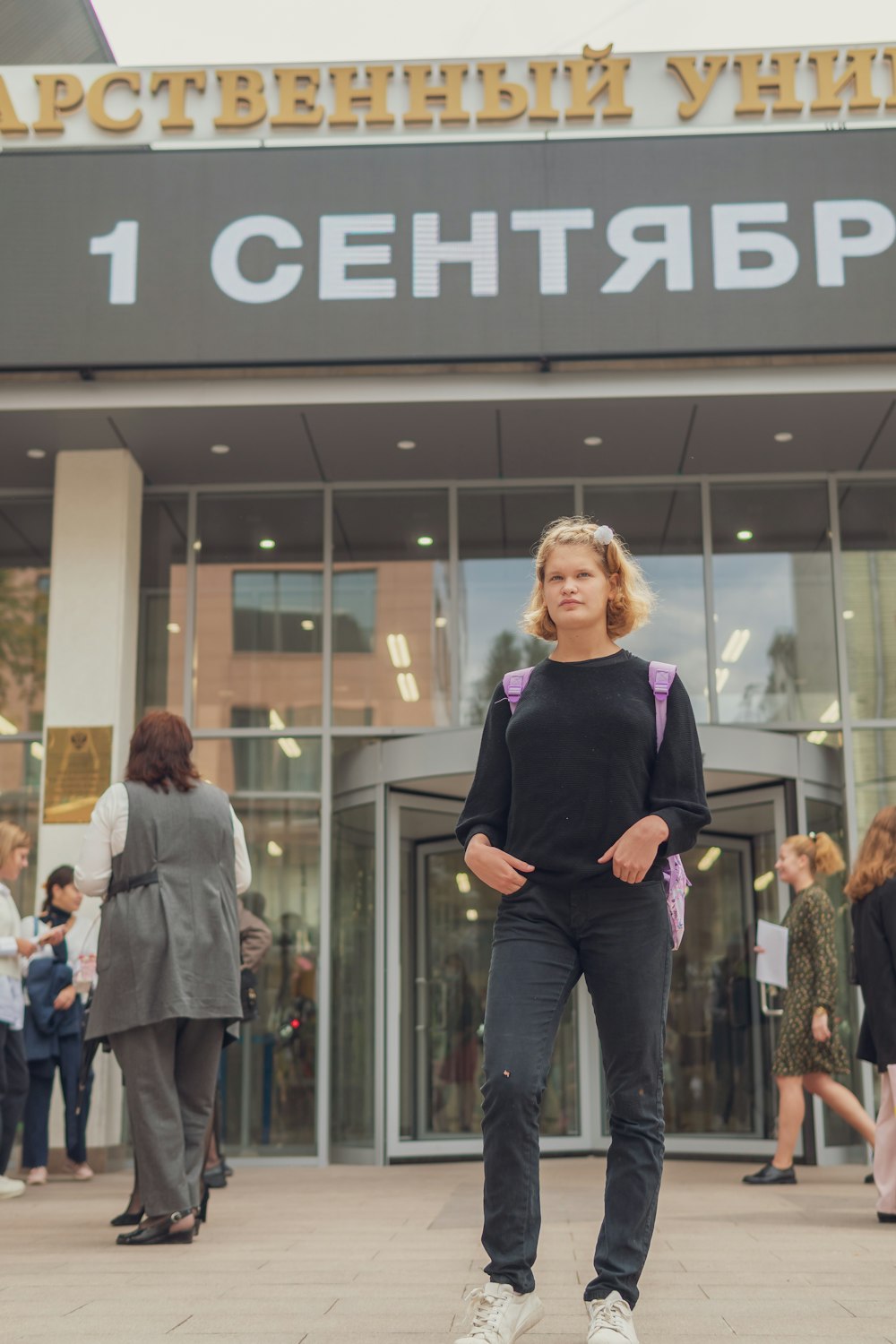 woman in black long sleeve shirt and black pants standing beside glass wall