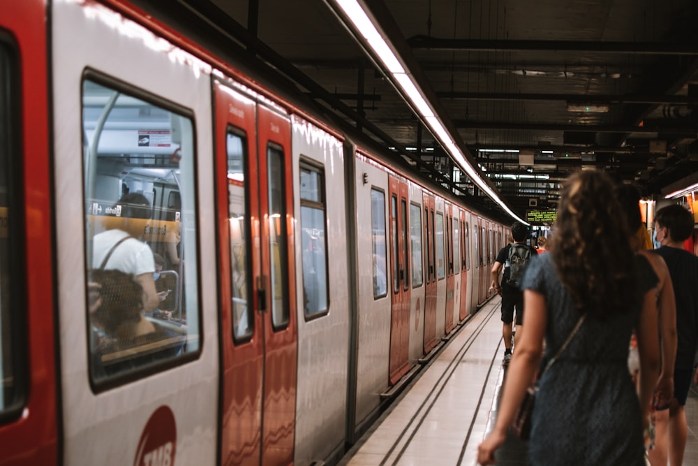 woman in black jacket standing beside red and white train