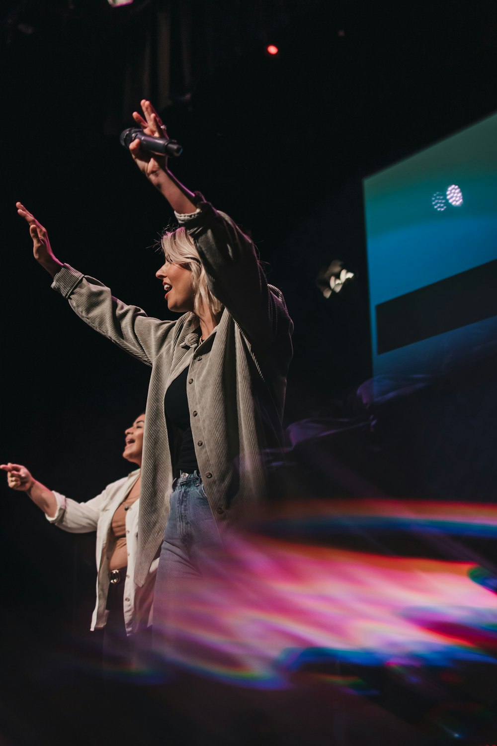 woman in gray coat singing on stage