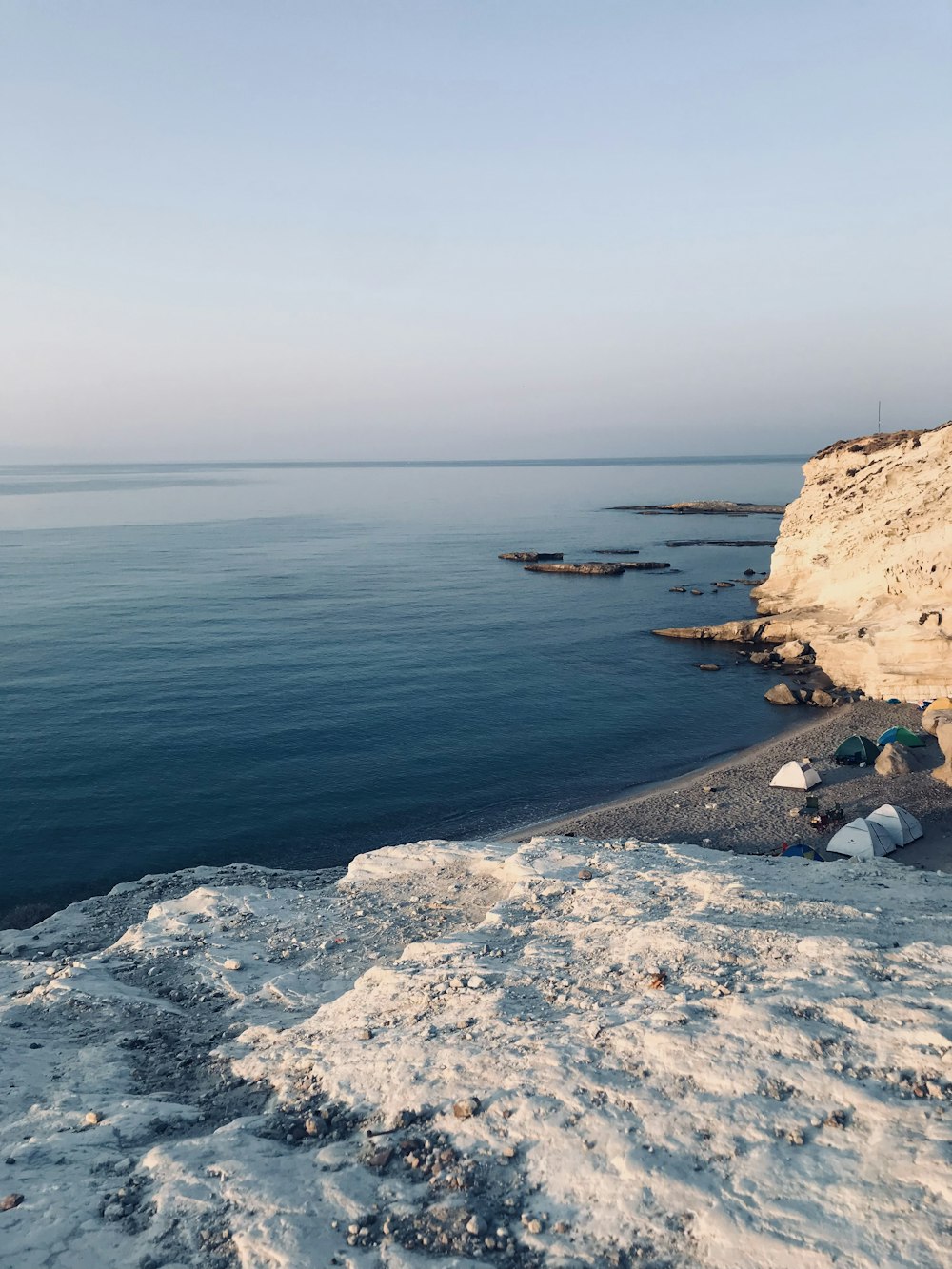 people sitting on rock formation near sea during daytime