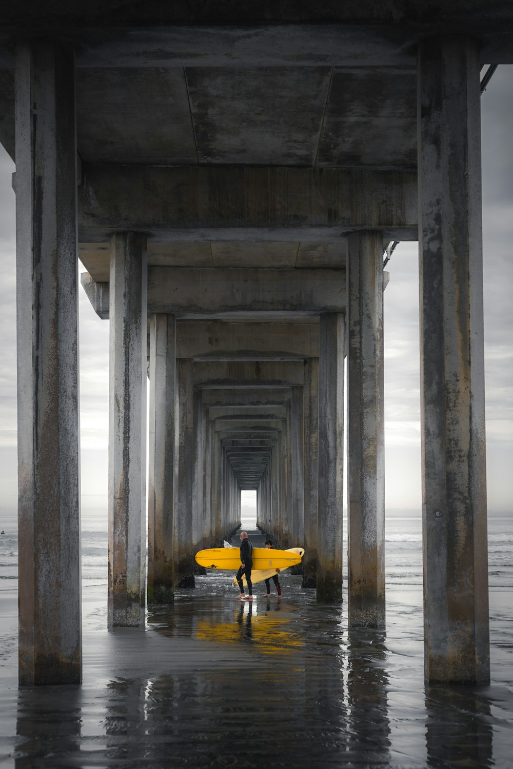 person in yellow kayak on body of water under bridge