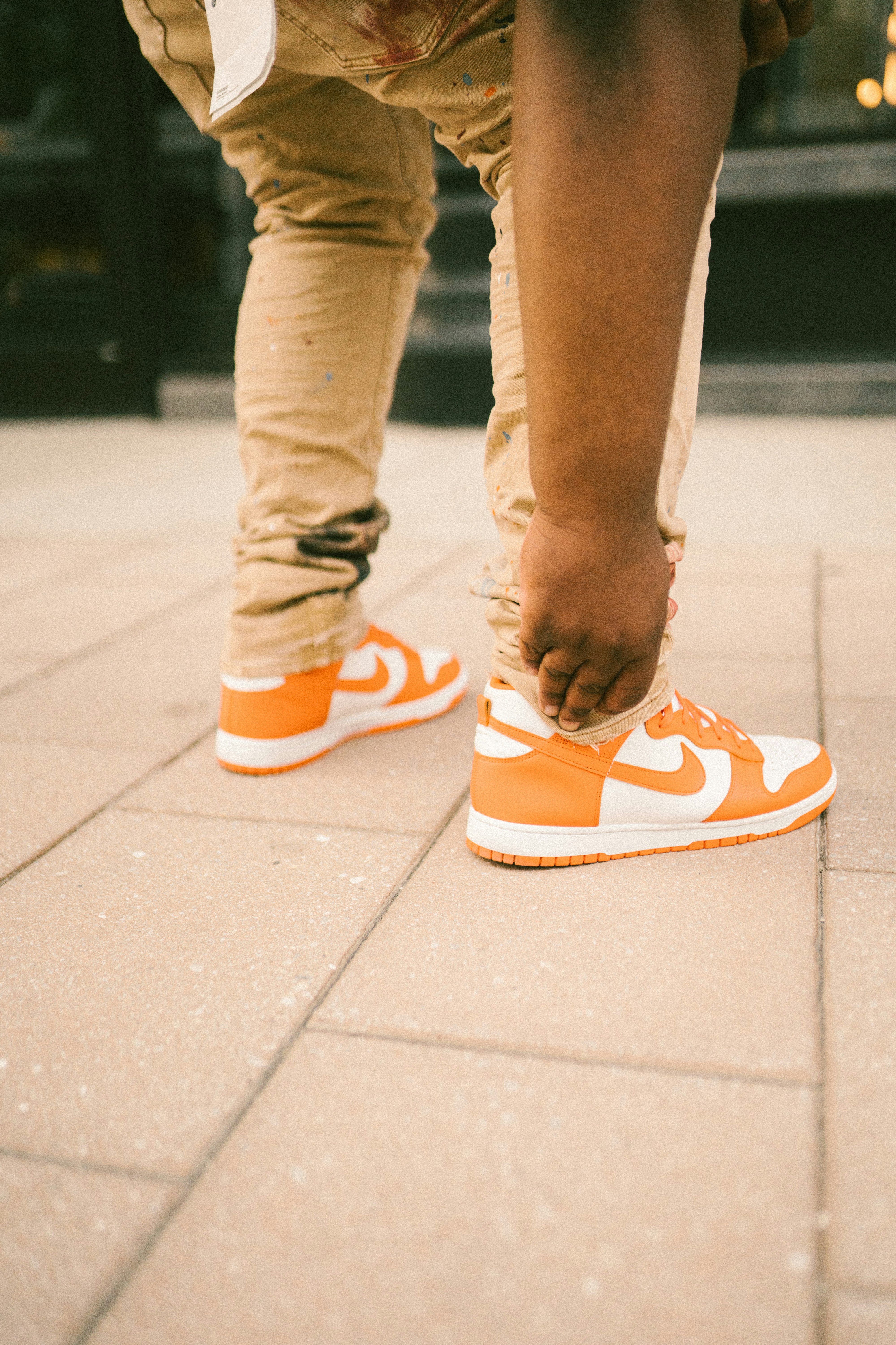 person in brown pants and white nike sneakers