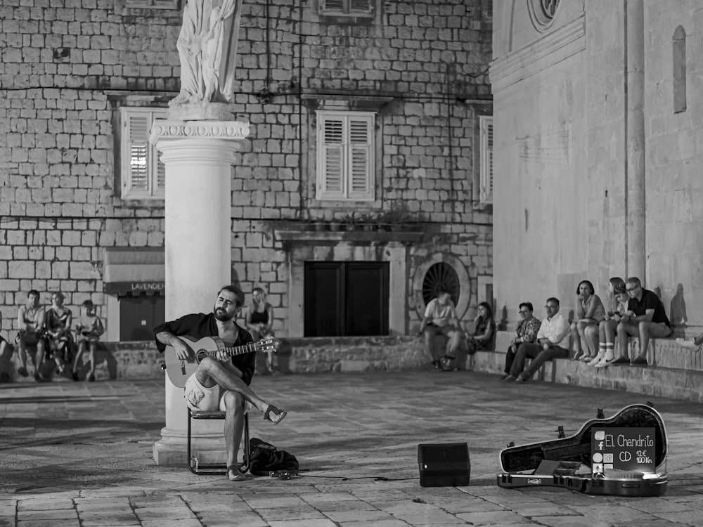 grayscale photo of man playing guitar