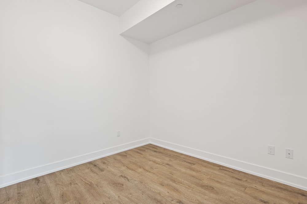 pintura de parede branca perto do piso de parquet de madeira marrom