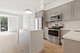 A modern kitchen with dark grey cabinets and beige accents.