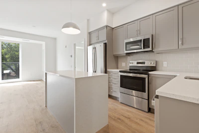 Open-plan kitchen with stainless steel appliances and natural light pouring in.