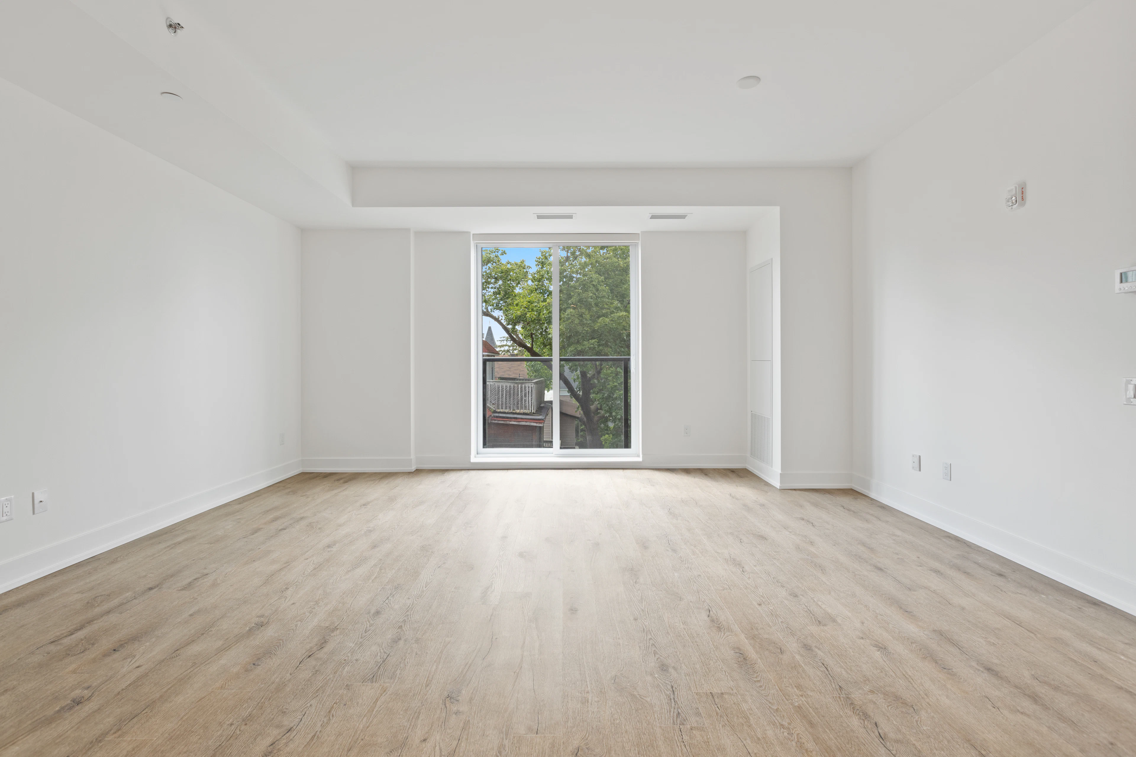 Empty living room with light wood floors and a glass door