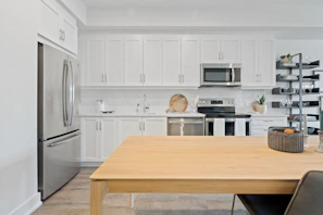 A sleek stainless steel refrigerator with a digital display, set in a bright modern kitchen.
