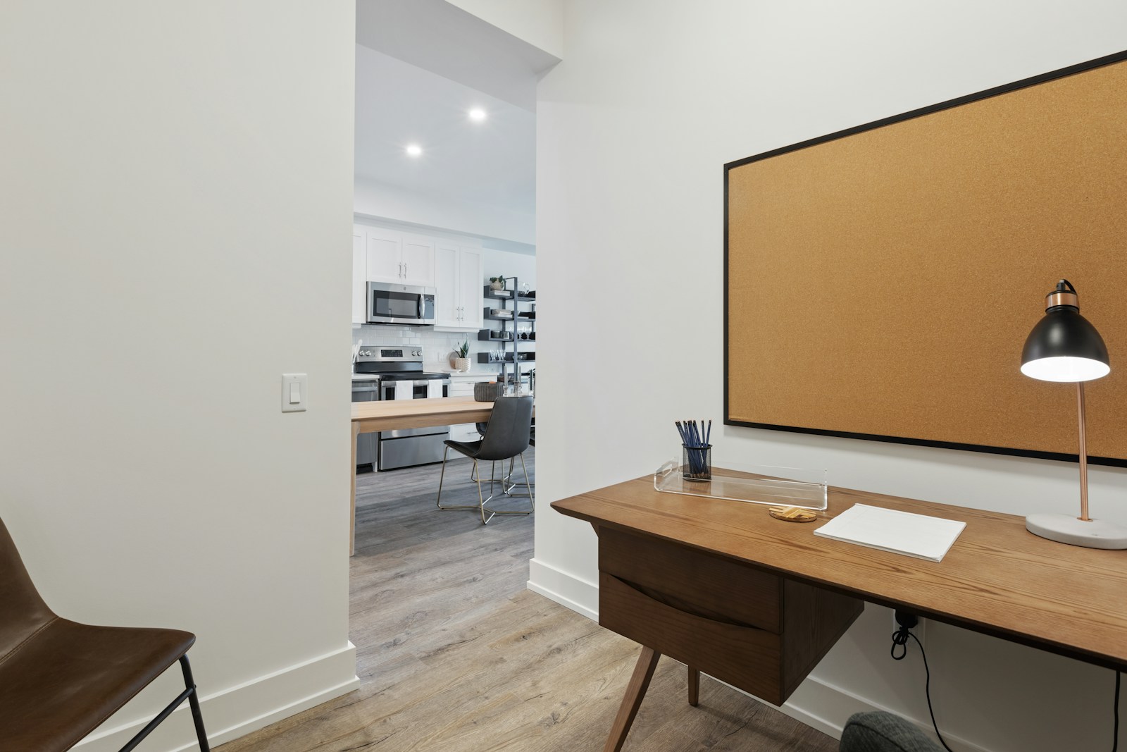 small home office nook in apartment with corkboard and warm task lamp