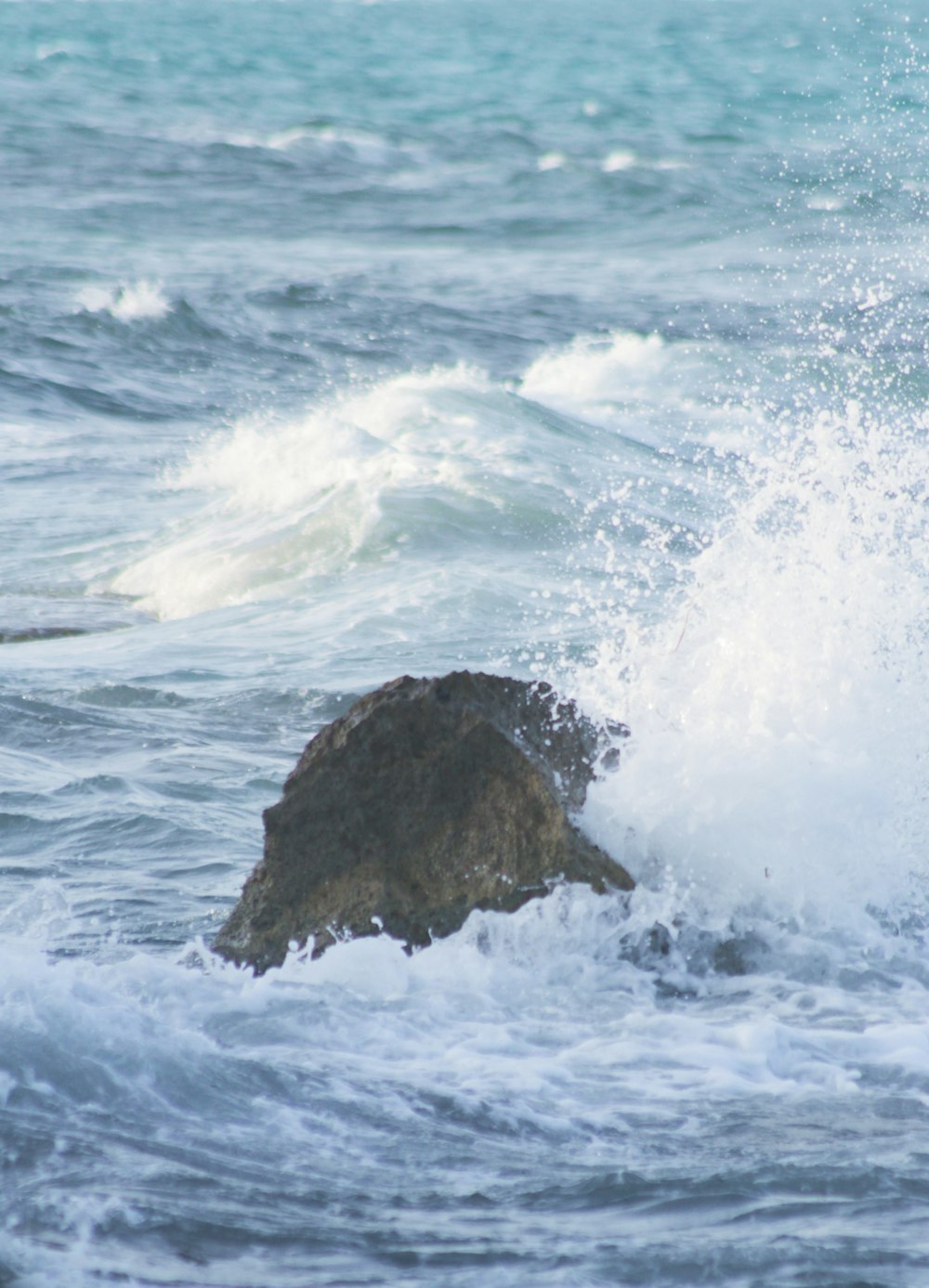ocean waves crashing on brown rock formation during daytime
