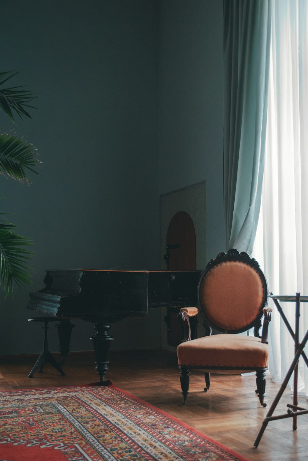 茶色のパッド入り椅子の横に茶色の木製グランドピアノ