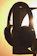 Close-up of a sleek black and gold wireless headphone resting on a floating shelf with warm amber lighting.
