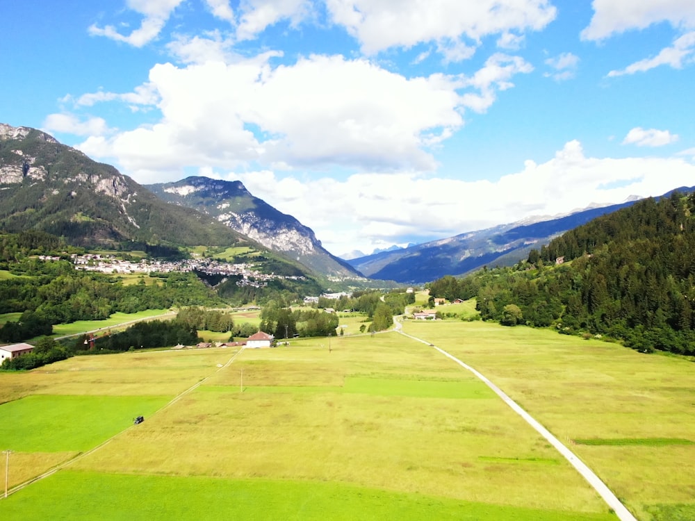 green grass field near green mountains under blue sky during daytime