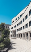brown concrete building near green trees under blue sky during daytime