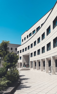 brown concrete building near green trees under blue sky during daytime