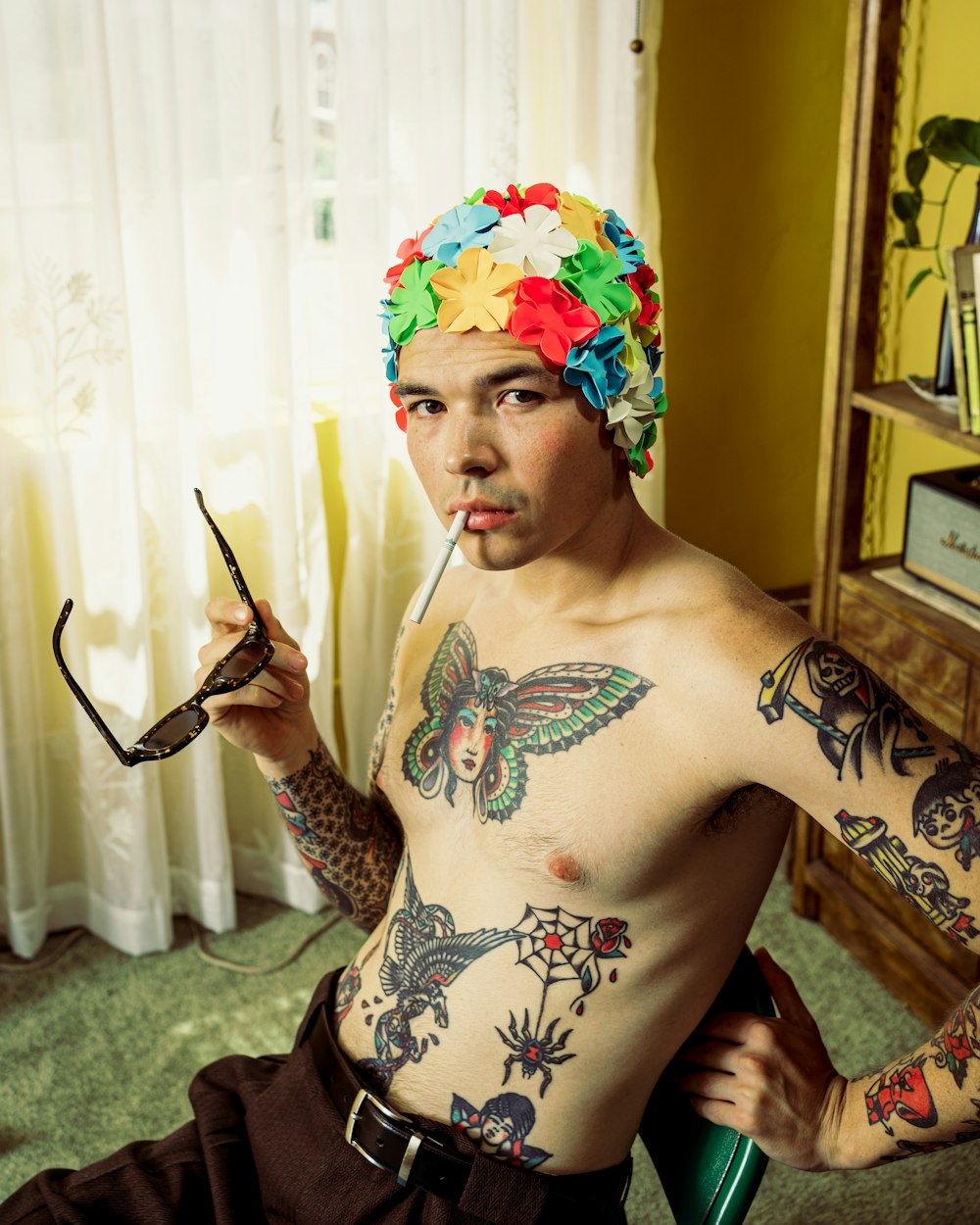 topless man with black and red floral tattoo holding black handled scissors